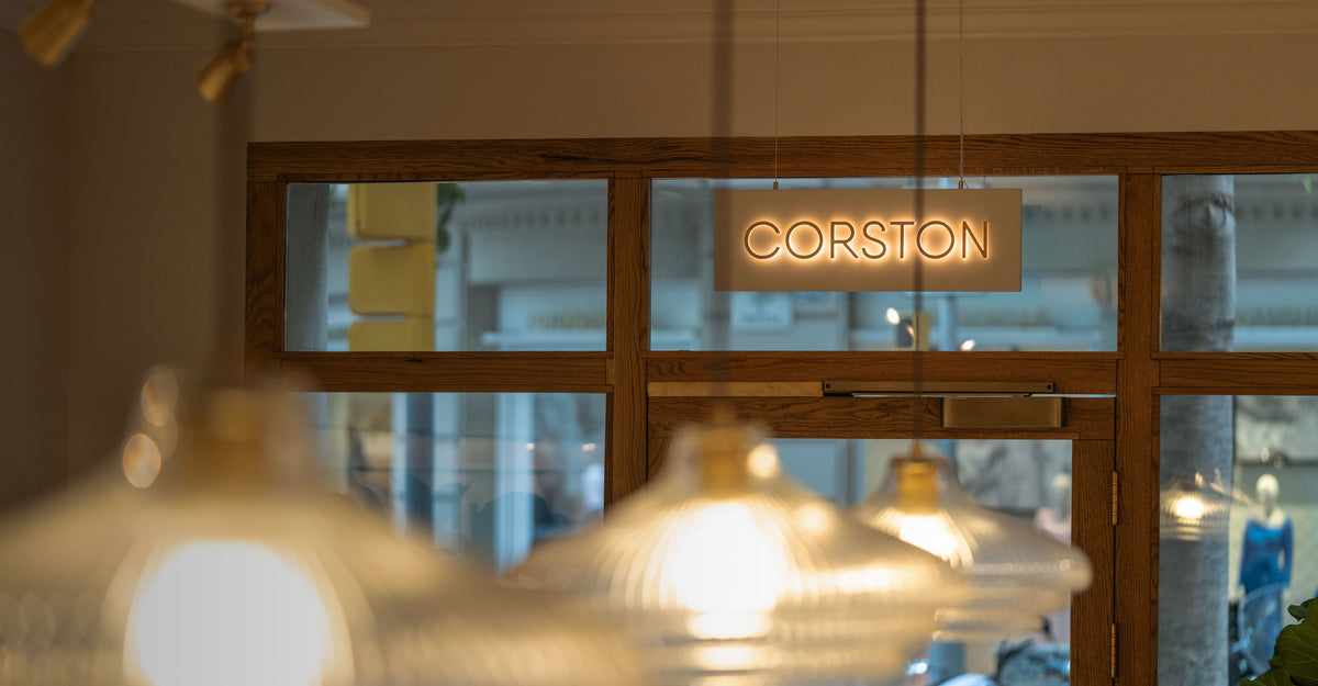 Glass door with 'Corston' sign and blurred interior lights